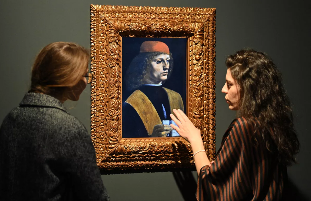 Des visiteurs devant une reproduction numérique du Portrait de musicien de Léonard de Vinci