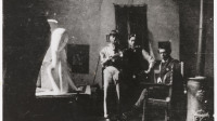 "Zadkine dans son atelier, à la Ruche, en compagnie de deux visiteurs dont le peintre Foujita (à gauche)". Photographie anonyme, 1912. Paris, musée Zadkine.  Dimensions : 8,1 x 10,8 cm