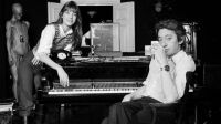 Paris - 15 dÈcembre 1971 - Chez eux, rue de Verneuil dans le 7e arrondissement, portrait du chanteur Serge GAINSBOURG fumant une cigarette assis devant son piano, prËs de sa compagne Jane BIRKIN accoudÈe ‡ l'instrument