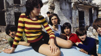 Jeune fille assise sur le capot d'une voiture entourée de garçons et terrain vague près de la rue Rampal. Quartier de Belleville. Paris (XIXème arr.). Photographie de François-Xavier Bouchart (1946-1993). Tirage couleur sur papier photographique Fujicolor. Entre 1968 et 1975. Paris, musée Carnavalet.