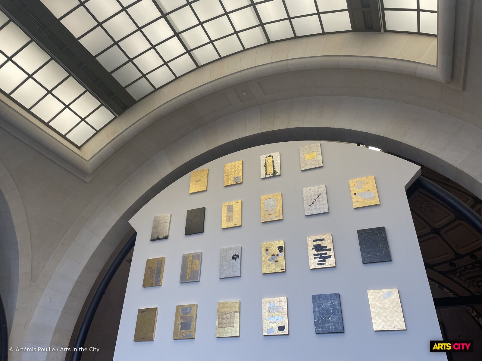 Mur de peintures caviardées à la feuille d'or et de platine de Jenny Holzer accroché sous la verrière du musée d'Orsay
