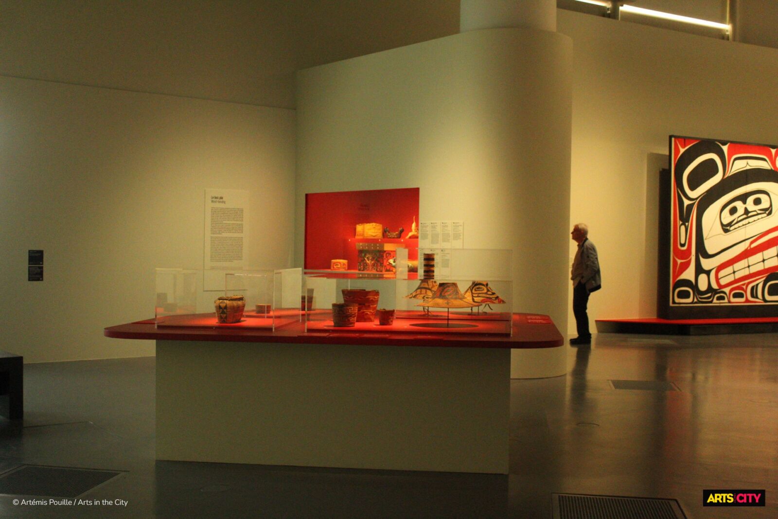 Vitrine de vanneries et d'objets du quotidien devant une grande peinture héraldique, exposition Premières Nations au musée du quai Branly - Jacques Chirac
