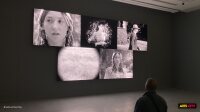 Un visiteur face au mur de cinq écrans noir et blanc de Stan Douglas dans l'exposition Parallax au Jeu de Paume